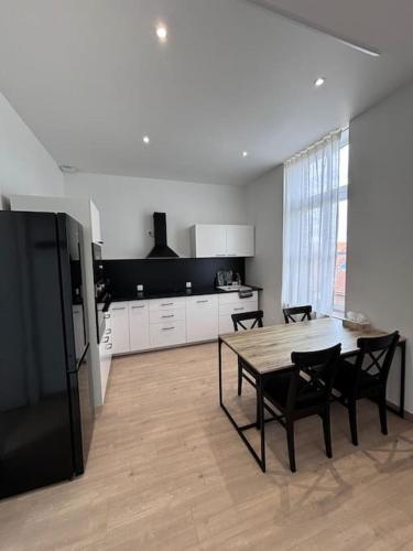 une cuisine avec une table, des chaises et un réfrigérateur dans l'établissement Duplex neuf à 15 min de LILLE, à Noyelles-lès-Seclin