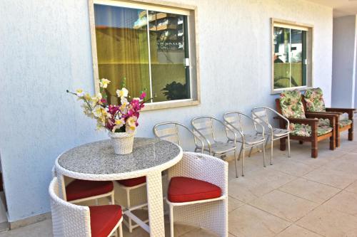 una mesa con un jarrón de flores en un patio en MDJ Suítes, en Cabo Frío