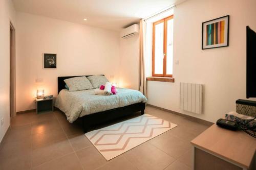 a bedroom with a bed with a pink stuffed animal on it at Appart 5 Charmant 2 pièces avec parking in Aix-les-Bains