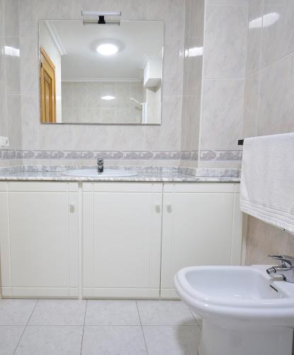 a white bathroom with a sink and a mirror at GALIHOST - Apartamento en el casco histórico de Cambados in Cambados