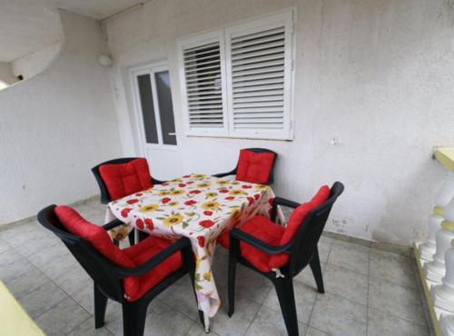 a dining room table with four red chairs and a table at Apartments Zora in Lopar