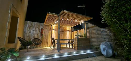 stół i krzesła na drewnianym tarasie w nocy w obiekcie Gîte 4 personnes avec piscine et bain nordique proche des plages du débarquement w mieście Le Manoir