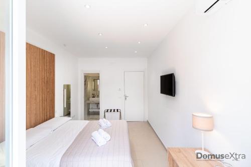a white bedroom with a bed and a tv on a wall at Olivia's Home By DomusExtra in Naples
