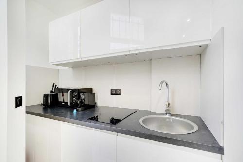 une cuisine blanche avec un évier et un micro-ondes dans l'établissement Elegant Studio - 2P-Next to Place Pigalle, à Paris