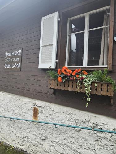 a window with flowers on the side of a building at Chalet Maithili Lauterbrunnen -152-Year-Old Majestic Chalet in Lauterbrunnen