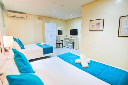 a hotel room with two beds and a television at Holiday Suites Business District - formerly Empire Suites Hotel in Puerto Princesa City
