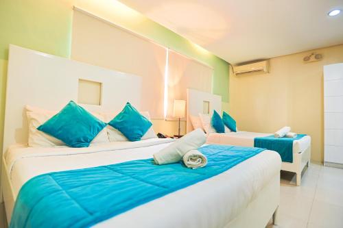 a bedroom with two beds with blue pillows at Holiday Suites Business District - formerly Empire Suites Hotel in Puerto Princesa City