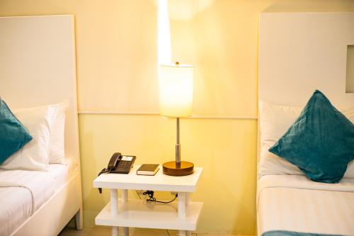 a lamp on a table next to a bed with a phone at Holiday Suites Business District - formerly Empire Suites Hotel in Puerto Princesa City