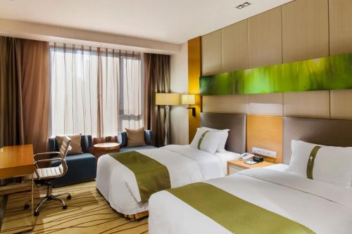 a hotel room with two beds and a desk at Holiday Inn Panjin Aqua City by IHG in Panjin