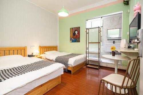 a bedroom with two beds and a table and a chair at Changsha Fuxiangyuan International Hostel in Changsha