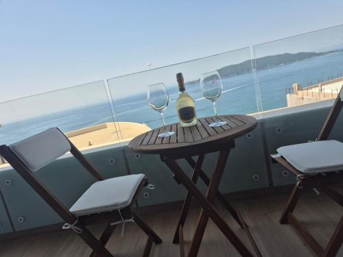 a table with a bottle of wine and two chairs at Rafailovici Beachfront Apartment in Budva