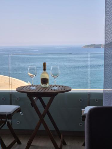 a table with two glasses and a bottle of wine at Rafailovici Beachfront Apartment in Budva