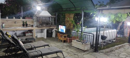 a patio with a tub and chairs and a tv at Anna's Summer House in Nea Kalikratia