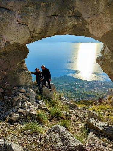 two people standing on a cliff looking through a cave at Perfect holiday in Vila Hany home in Šestanovac
