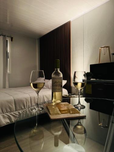 a bottle of wine on a table with two glasses at Cedro lodge in Fraijanes