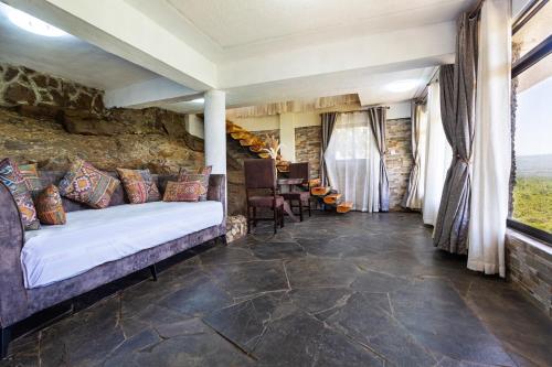 a bedroom with a bed and a stone wall at Sleeping Warrior Camp Elementaita in Nakuru