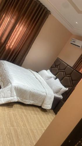 a bed with white sheets and pillows in a room at Claramojisola -Eunice Apartment in Abuja