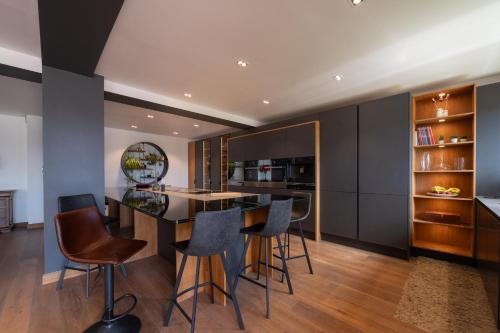 an open kitchen with black cabinets and a bar with stools at Villa Ty Castel - Arradon in Ploeren