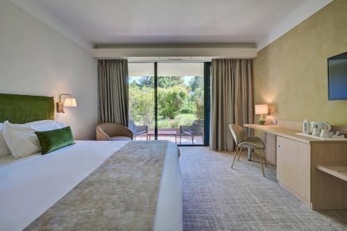a hotel room with a bed and a balcony at Best Western Sévan Parc Hôtel in Pertuis