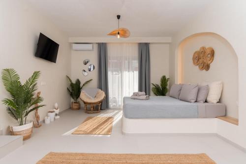 a white living room with a bed and some plants at IOSIF LUXURY ROOMS CENTER in Neos Marmaras