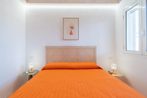 an orange bed in a white bedroom with two lamps at Agrivillage San Lorenzo in San Lorenzo