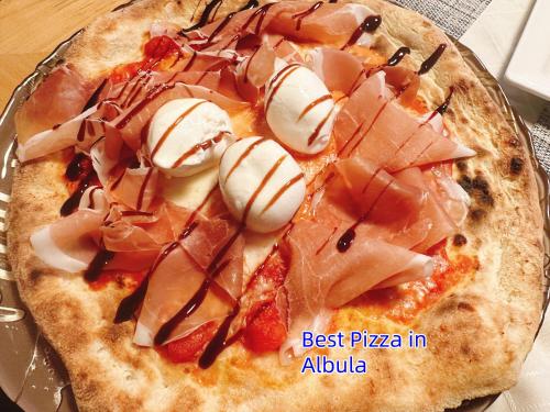 a pizza with meat and cream on a plate at Hotel Schöntal in Filisur