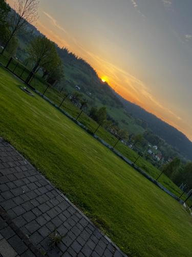 a sunset in a park with a fence and grass at Beskidzki Domek Kurów in Kurów