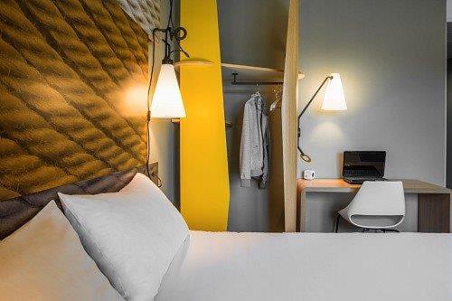 a bedroom with a bed and a desk with a laptop at ibis Tarbes Odos in Odos