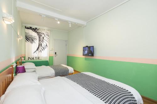 a bedroom with two beds and a tv on the wall at Changsha Fuxiangyuan International Hostel in Changsha