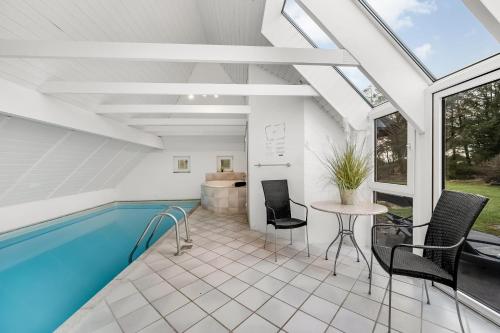 a house with a swimming pool and a table and chairs at Large Pool House With 6 Person Outdoor Spa 1015 in Ringkøbing