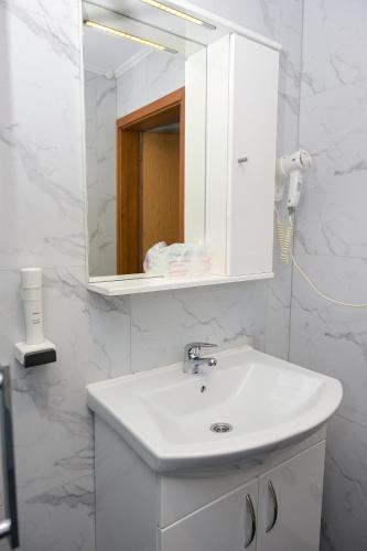 a white bathroom with a sink and a mirror at Motel Plaza in Jajce