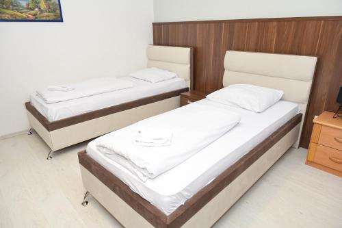 two twin beds in a room with wooden walls at Motel Plaza in Jajce