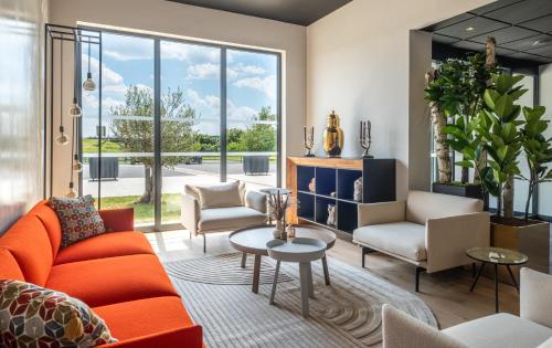 a living room with orange furniture and a large window at Kyriad Chateauroux Nord - Aéroport in Déols