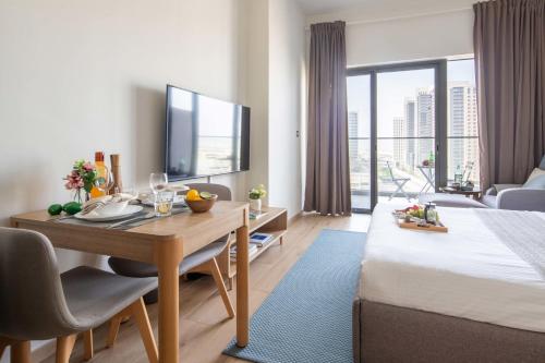 a hotel room with a bed and a dining table and a television at Frank Porter - Aura by Azizi in Dubai