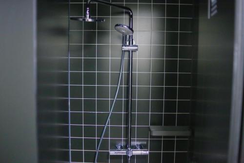 a shower with a shower head and green tiles at Dayin Youth Hostel - Old Town & People's Square& Rail Hub -Social Area -Bar -Café -Gym -Free Laundry Luggage Storage -24H Front Desk -English Service in Shanghai