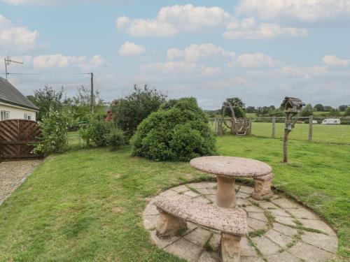 a stone table and two benches in a yard at The Turbles - Swallows Nest in Castlemorton