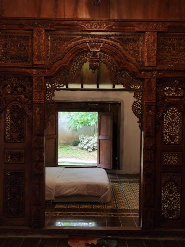 a bedroom with a bed and a large window at Wulenpari EcoVillage in Sambipilu