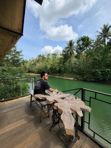 a man sitting at a table on a deck at Wulenpari EcoVillage in Sambipilu