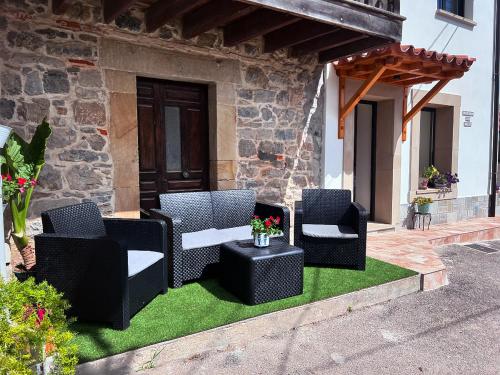 a patio with four chairs and a table on grass at La casina de Tomás in Colunga