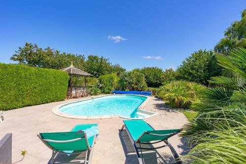 une piscine avec deux chaises longues et une table dans l'établissement La Desirade, à Saint-Agnant