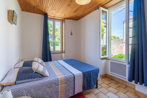 a bedroom with a bed and two windows at La Desirade in Saint-Agnant