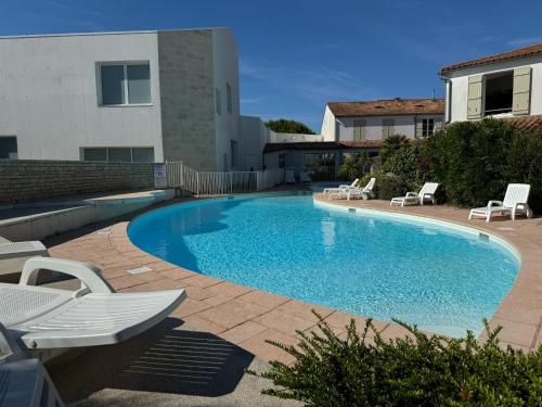 une grande piscine avec des chaises et une maison dans l'établissement L'Ânnerie - Piscine, à La Couarde-sur-Mer