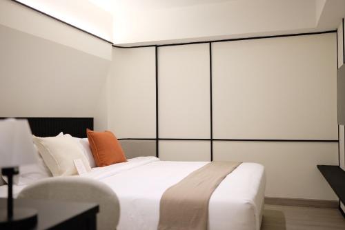 a bedroom with a white bed with an orange pillow at Pillow B Hotel in Ban Zong Katiam