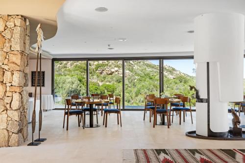 a dining room with tables and chairs and a large window at Hotel delle Rose a Luxury Boutique Hotel in Porto Cervo