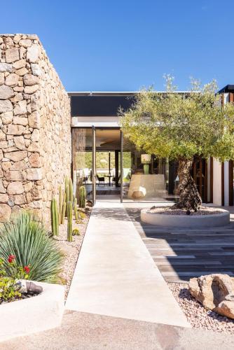 a house with a stone wall and a walkway with cactus at Hotel delle Rose a Luxury Boutique Hotel in Porto Cervo