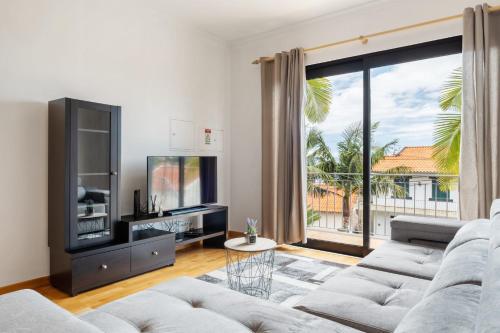 a living room with a couch and a large window at Atlantic Ocean Breeze in Ponta do Sol