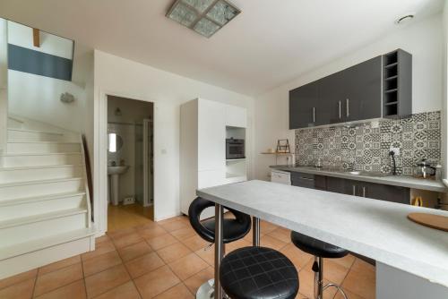 une cuisine avec un comptoir et des tabourets dans une pièce dans l'établissement Suisse Normande Refuge - Maison à la campagne 6p, à Amayé-sur-Orne