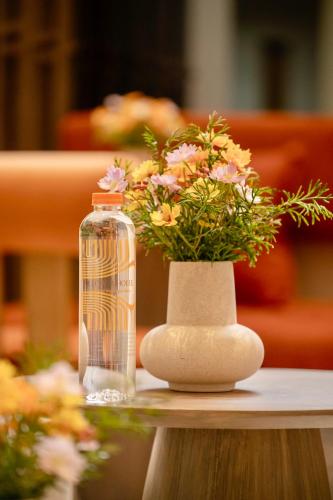 a bottle of water next to a vase of flowers at Pillow B Hotel in Ban Zong Katiam