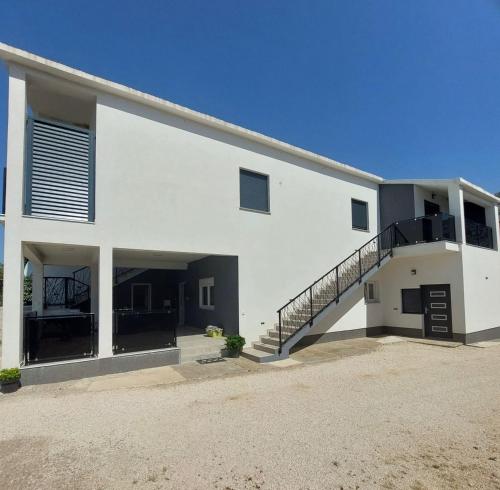 a white building with a staircase in front of it at Apartmani Karla Paklenica in Starigrad-Paklenica