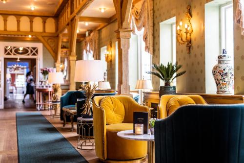 a lobby with yellow chairs and tables in a building at Dyvig Badehotel in Nordborg